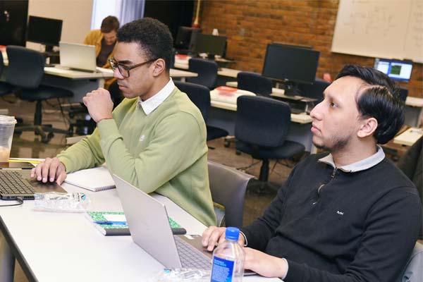 Two students working on laptops in a CIS classroom