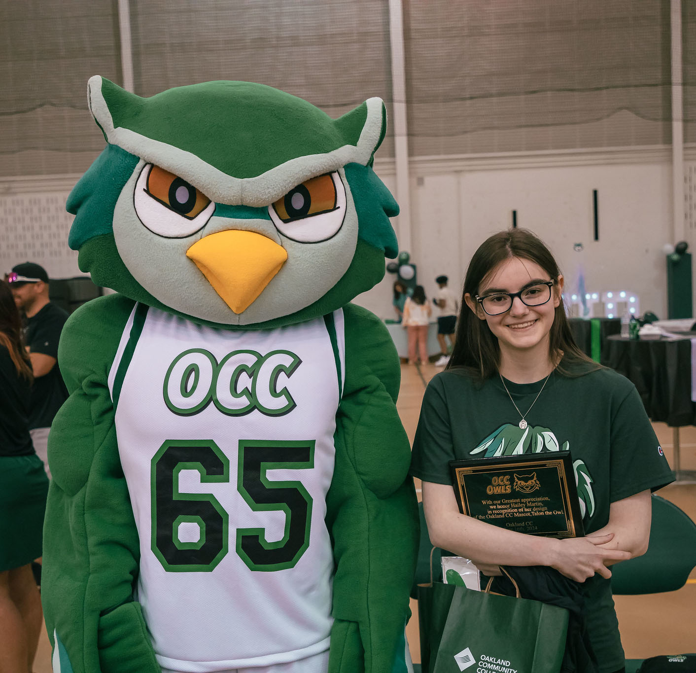 OCC student Hailey Martin holding plaque next to Talon the Owl